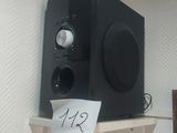 une enceinte noire posée sur une étagère, avec un bout de papier collé dessus
