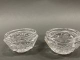 two clear glass bowls on a table with a black background