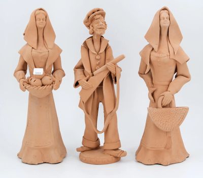 trois figurines en argile représentant une femme et un homme tenant un panier