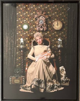 a picture of a woman sitting in a chair with a clock on the wall behind her