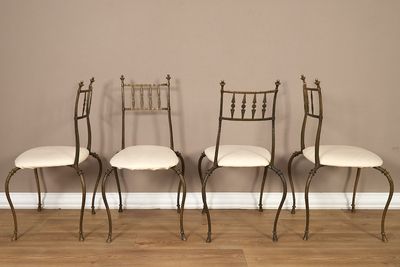 trois chaises en métal avec des coussins blancs sont adossées à un mur marron