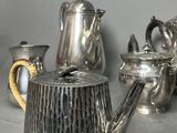 a silver tea pot sitting on a table next to other silver teapots
