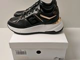 a pair of black and gold sneakers on top of a white box