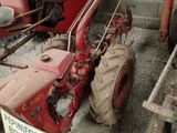 un tracteur rouge garé à côté d'une remorque sur laquelle est accrochée une pancarte