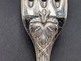 an old silver fork with a heart on it sitting on a table
