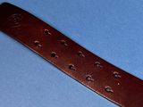 a close up of a brown leather watch strap on a blue surface