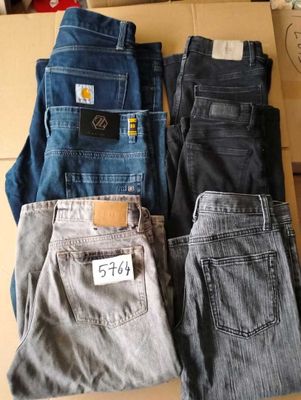 three pairs of men ' s jeans sitting on top of a cardboard box