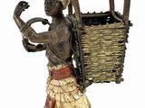 statue of a woman carrying a basket with a bird on her head