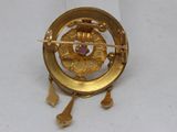 an image of a gold broochle with a pink stone in the center