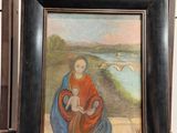 un tableau représentant une femme tenant un enfant dans ses bras, posé sur une table