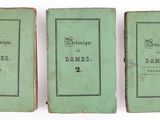 three old books are lined up in a row on a white surface