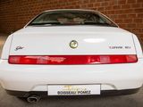 a white car parked in a garage with a brick wall behind it