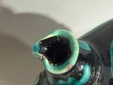 a black and blue vase sitting on a white surface