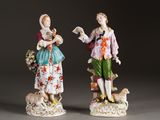 pair of porcelain figurines of a man and a woman with a dog