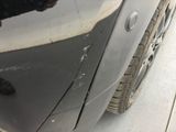 a person standing next to a car that has a dent in it