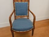 a wooden chair with a blue upholstered seat in the corner of a room