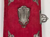 an old red book with a silver shield on it on a white surface