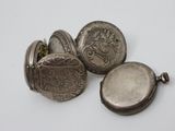 three antique silver pocket watches sitting next to each other on a white surface