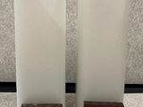 deux grands vases blancs posés sur une table, avec des socles en bois