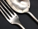 two forks and a spoon on a black table