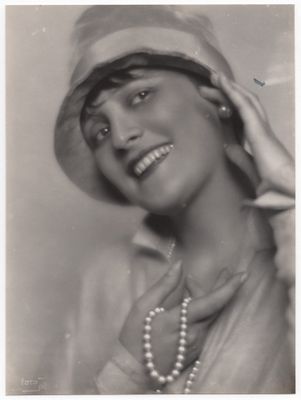 une vieille photo en noir et blanc d'une femme portant un chapeau et un collier de perles