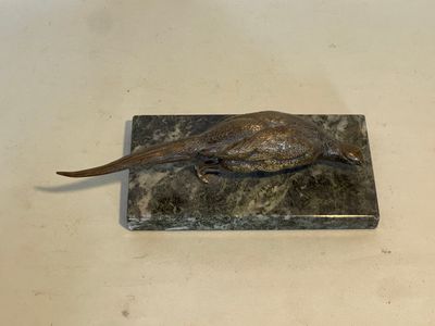 statue d'un faisan posée sur un socle en marbre, elle-même posée sur une table