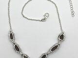 a close up of a necklace on a white surface with a chain