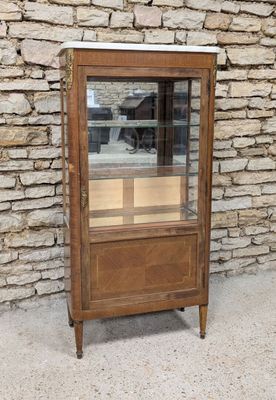 a small display case with a glass door in front of a stone wall