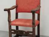 une vieille chaise en bois dont l'assise est recouverte de tissu rouge
