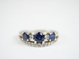 a close up of a blue sapphire and diamond ring on a white surface