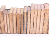 several old books stacked on top of each other on a white surface