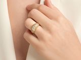 the woman is wearing a gold ring and a white shirt