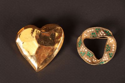 deux bijoux en or et émeraude posés sur un fond noir