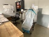 a desk with a chair and a chair covered with a plastic sheet