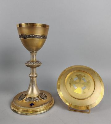 un calice et une assiette en laiton posés sur une table avec un fond gris