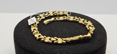 un bracelet en or posé sur une boîte noire, sur une surface blanche