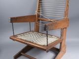 an old wooden chair with a roped seat on a stand