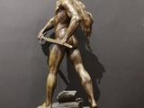 bronze statue of a man with a sword on a wooden base