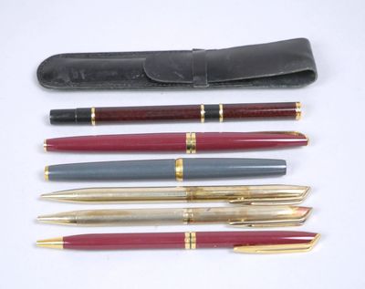 trois stylos et un étui à stylos posés sur une surface blanche