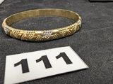 un bracelet en or posé sur une table noire, sur lequel figure le chiffre 11