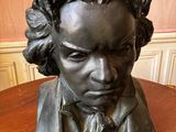statue représentant le buste d'un homme aux cheveux bouclés, posée sur une table en bois