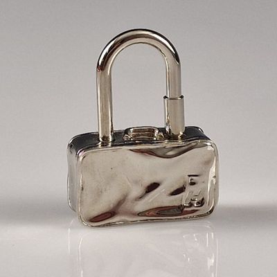 un petit cadenas argenté muni d'une poignée, posé sur une surface blanche