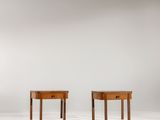 two small wooden tables with drawers sit on a white surface