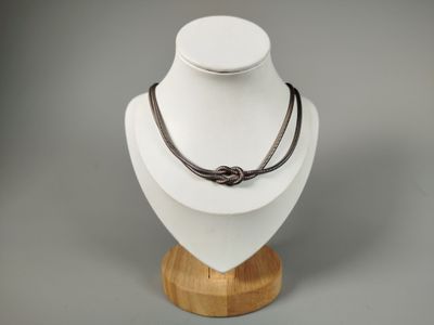 necklace with a knot on a wooden stand on a gray background