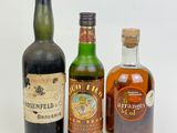 three bottles of liquor are lined up on a white surface