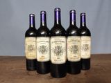 six bottles of wine are lined up on a wooden table