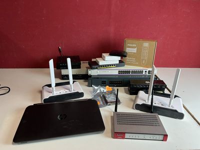 une table sur laquelle se trouvent un ordinateur portable, un autre ordinateur portable et d'autres appareils électroniques