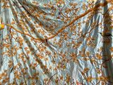 un lit recouvert d'une couette à motifs floraux bleus et jaunes, sur laquelle sont posées une paire de ciseaux