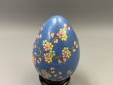 an image of a blue and pink decorated egg on a black stand
