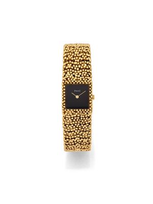 a close up of a gold bracelet watch with a black face